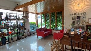 Un hall de hotel con un sofá rojo, techo de madera y una pared con el cartel 'J2 Hotel'.