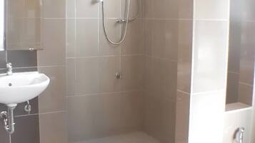 A modern bathroom with a shower, a sink, and a towel rack.