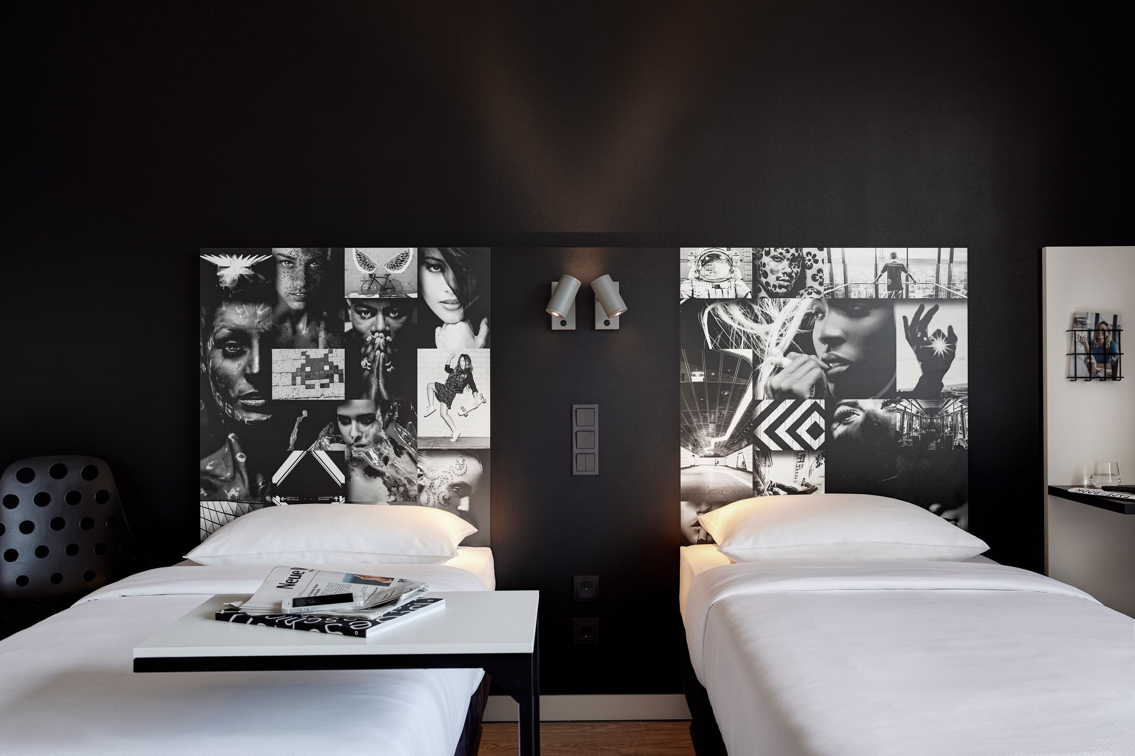 Habitación de hotel con dos camas, un mural grande en la pared y una mesita con una revista.
