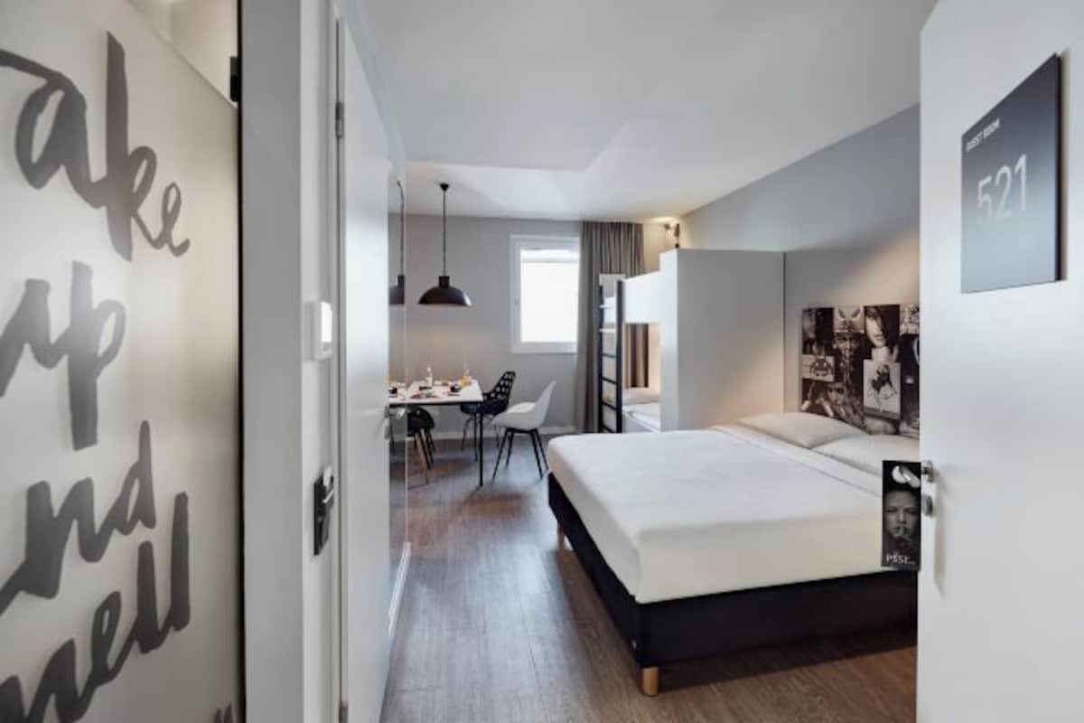 A modern hotel room with a bed, a desk, and a chair.