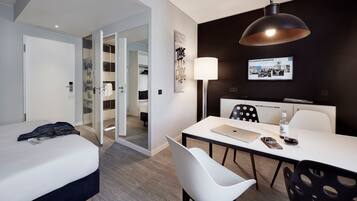 Une chambre d’hôtel moderne équipée d’un lit, d’un bureau, d’une chaise, d’une lampe et d’un téléviseur.