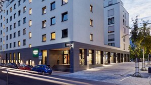 A modern hotel building with a flat facade, multiple windows, and a prominent entrance with steps. - LEGERE EXPRESS Bielefeld (Bielefeld)