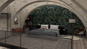 Une chambre à coucher comprenant un lit, une table de chevet, une chaise et un mur orné d’un motif de feuilles.