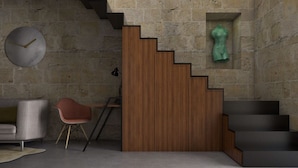 Un intérieur moderne avec un escalier, une horloge ronde, un canapé et un fauteuil.