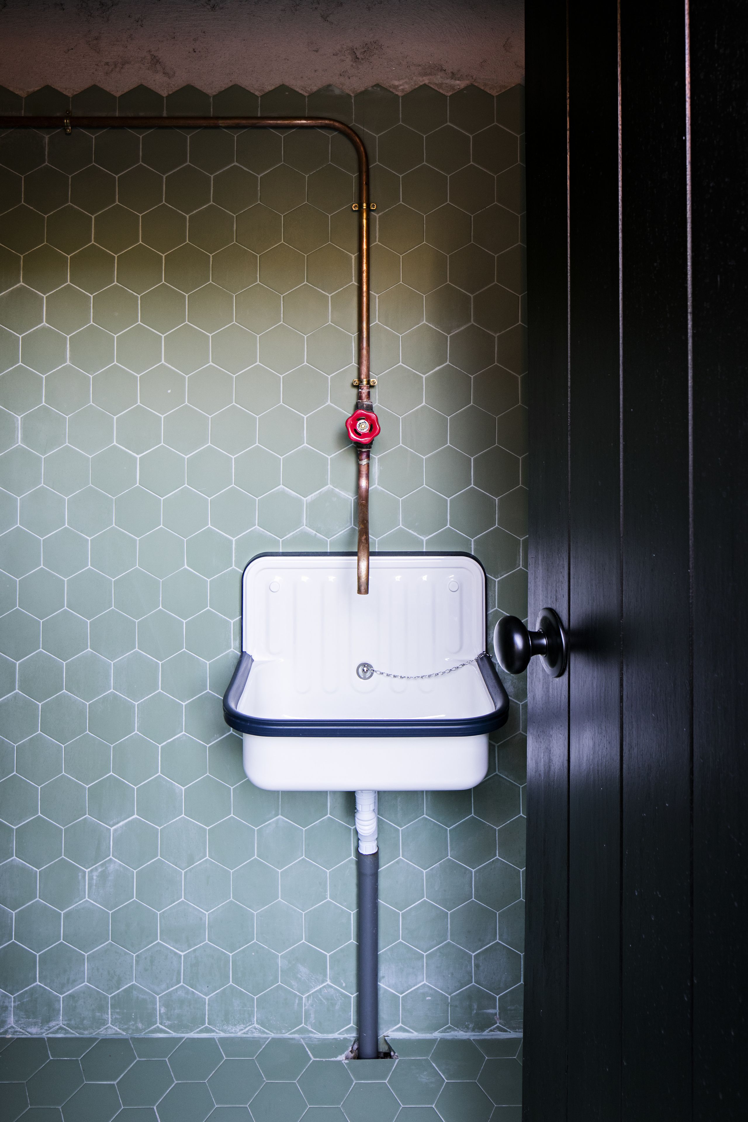 A bathroom with a white sink, a hexagonal tiled wall, and a door with a black handle.