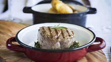 A red enameled cast iron pot with a roast on a wooden board.