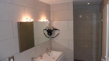 Een moderne badkamer met een grote spiegel, twee wastafels en een douche.