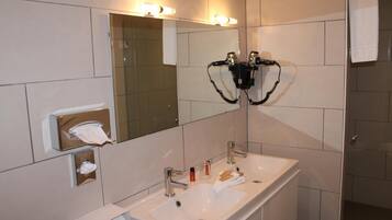 A modern bathroom with a large mirror, two sinks, and a towel dispenser.
