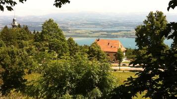 A house with a red roof, surrounded by lush greenery and a lake in the background.