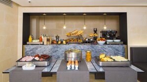 A buffet setup with various food items, including meats, cheeses, and baked goods, arranged on a marble countertop with hanging lights above. - Etoile de Pompadour (Beyssac)
