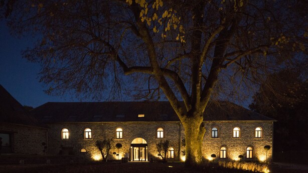 A stone building with multiple arched windows and a large tree in front. - Etoile de Pompadour (Beyssac)