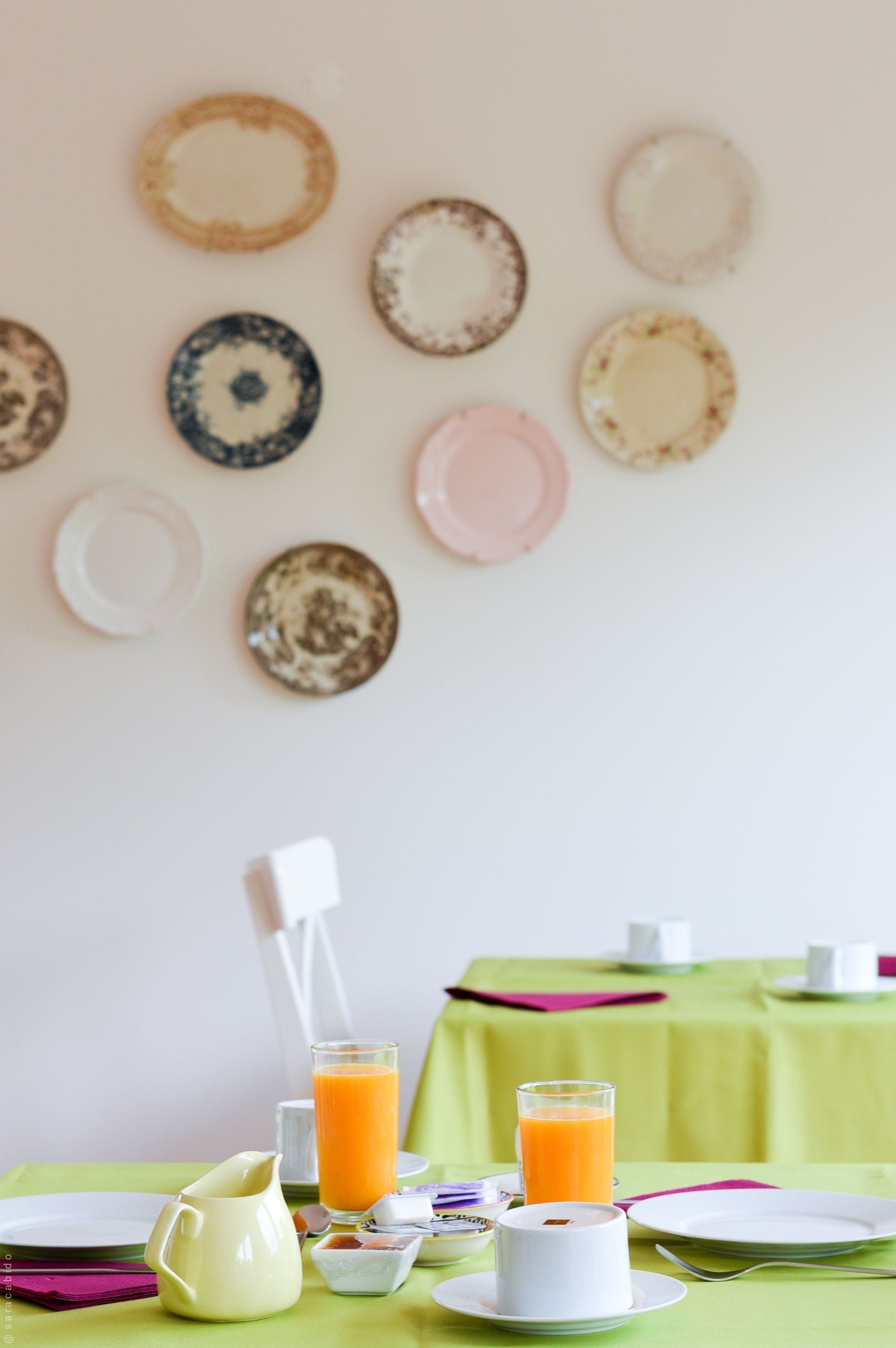 A breakfast table with plates, a pitcher, and glasses of orange juice.