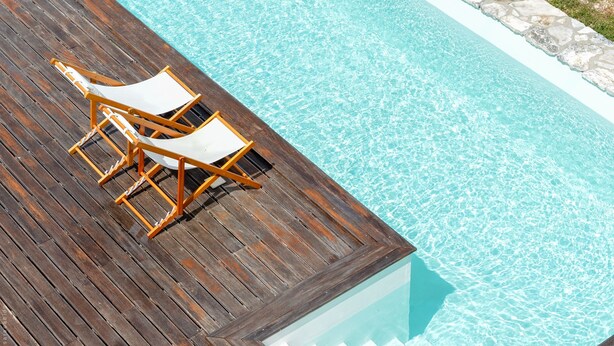 A wooden deck with two lounge chairs by a clear blue pool. - Retiro do Bosque Country House (Alcanena)