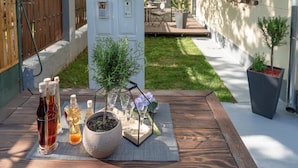 A patio with a wooden table set with drinks, a potted plant, and a small book. - Anastasia Suites Zagreb (Zagreb)