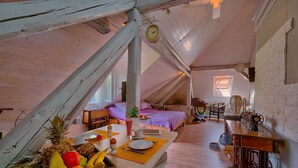 A rustic attic bedroom with a sloped ceiling, a bed, a dining table with breakfast items, and a vintage sewing machine. - Anastasia Suites Zagreb (Zagreb)