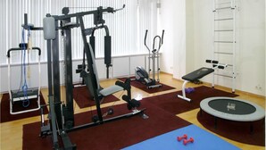 Une salle de sport équipée de matériel d’exercice, d’un banc, d’un trampoline et d’une barre de traction.