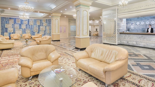 Un hall d’entrée spacieux, doté de fauteuils en cuir, d’un comptoir de réception et de panneaux muraux décoratifs.