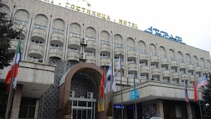 Un hôtel doté d’une grande entrée en arc de cercle, de nombreux balcons et de drapeaux.