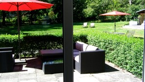 A patio area with outdoor furniture and two red umbrellas. - Haus Katharina - Hotel am Park (Bad Steben)