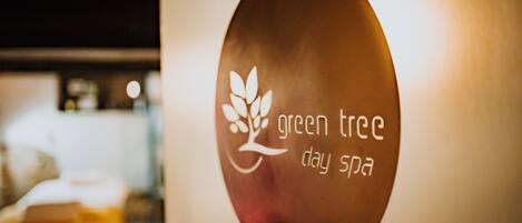 Un cartel con el texto 'green tree day spa' y un diseño de hoja.