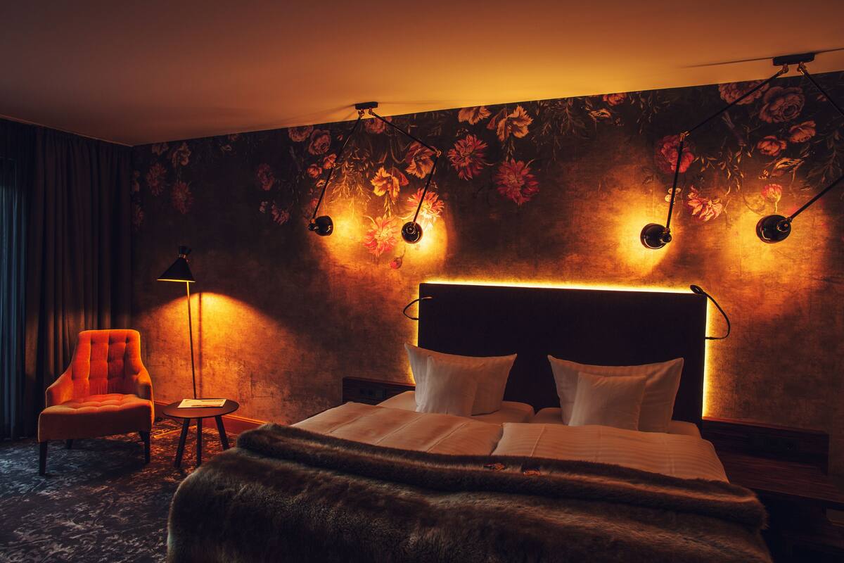 Une chambre d’hôtel avec un lit, une chaise, une petite table et une lampe.