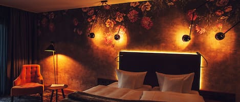 Una habitación de hotel con una cama, una silla, una mesita y una lámpara.