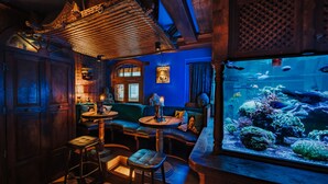 A cozy bar area with wooden furniture, a large aquarium, and a blue wall.