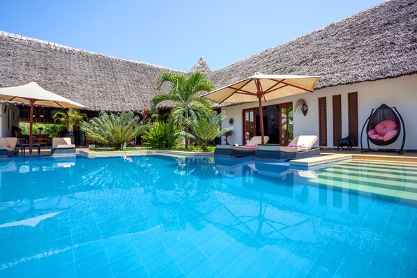 Alberca al aire libre, sombrillas en la alberca y camastros 