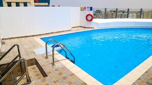 A rooftop swimming pool with clear blue water, a lifebuoy, and a city view. - The Town Hotel Doha (Doha)