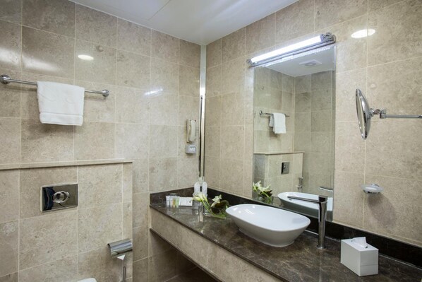 A modern bathroom with a large mirror, a sink, and a shower.