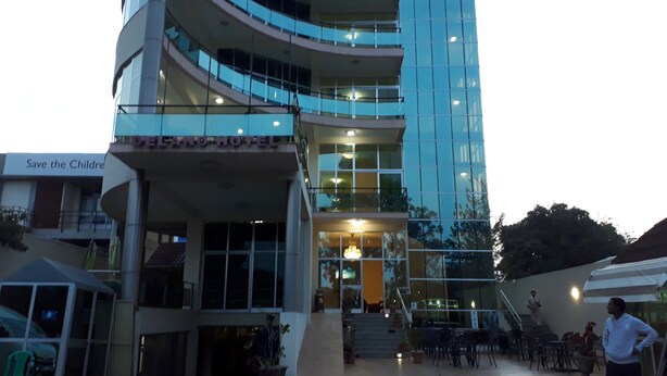 A multi-story hotel with a glass facade, outdoor seating area, and a sign reading "Save the Children". - Delano Hotel (Bahir Dar)