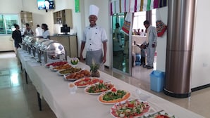 A buffet setup with various food items and a chef standing by. - Delano Hotel (Bahir Dar)