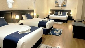 A hotel room with two beds, each with a headboard, bedside tables, lamps, and a large painting on the wall. - Delano Hotel (Bahir Dar)