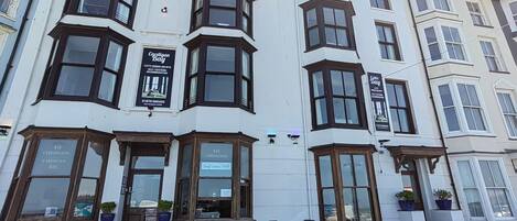 A corner building with bay windows, a cafe named 'Seafront Cafe', and a sign for 'Cardigan Bay' accommodation.
