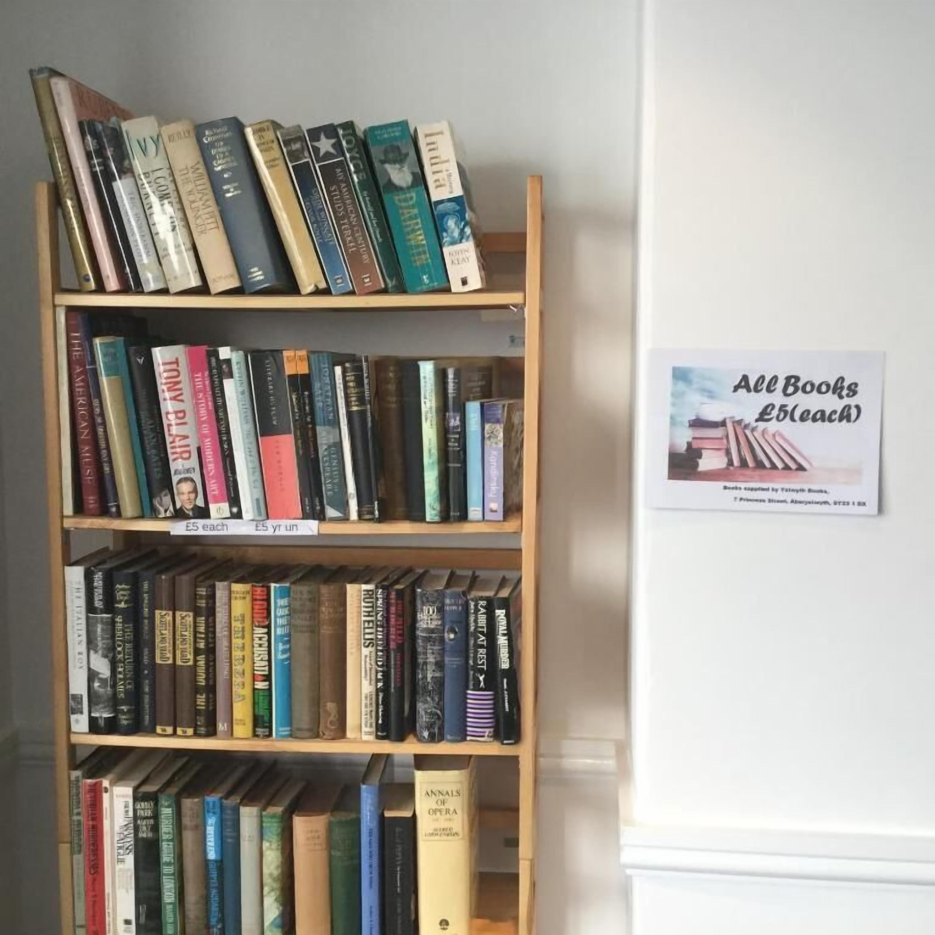 Une étagère à livres avec une pancarte indiquant : « Tous les livres à 5 £ l’unité ».