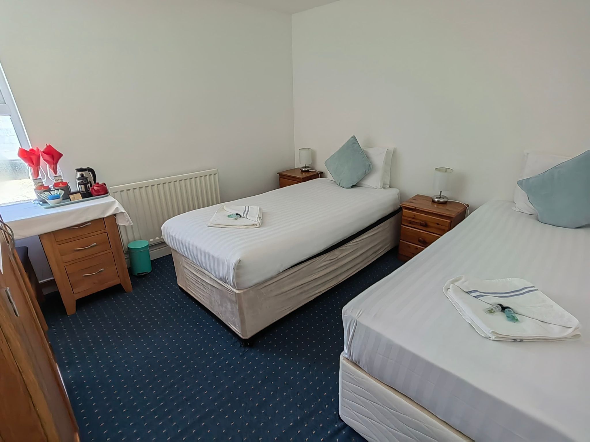 A hotel room with a bed, bedside tables, a desk, and a radiator.