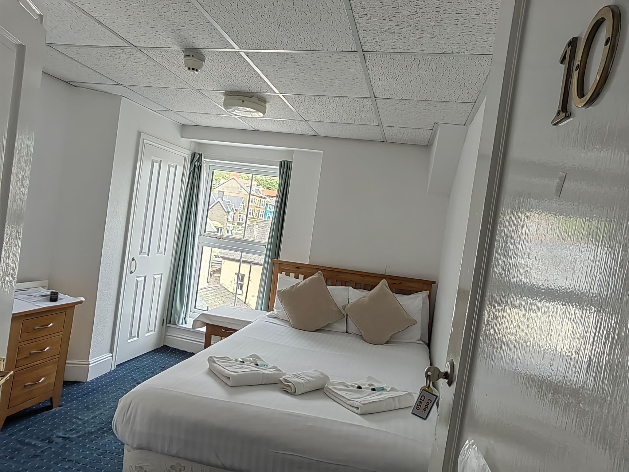 Ett hotellrum med en säng, ett nattduksbord, en garderob och utsikt över omgivningarna.
