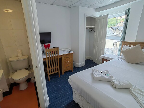 Une chambre d’hôtel comprenant un lit, un bureau, une chaise, une télévision et un placard.
