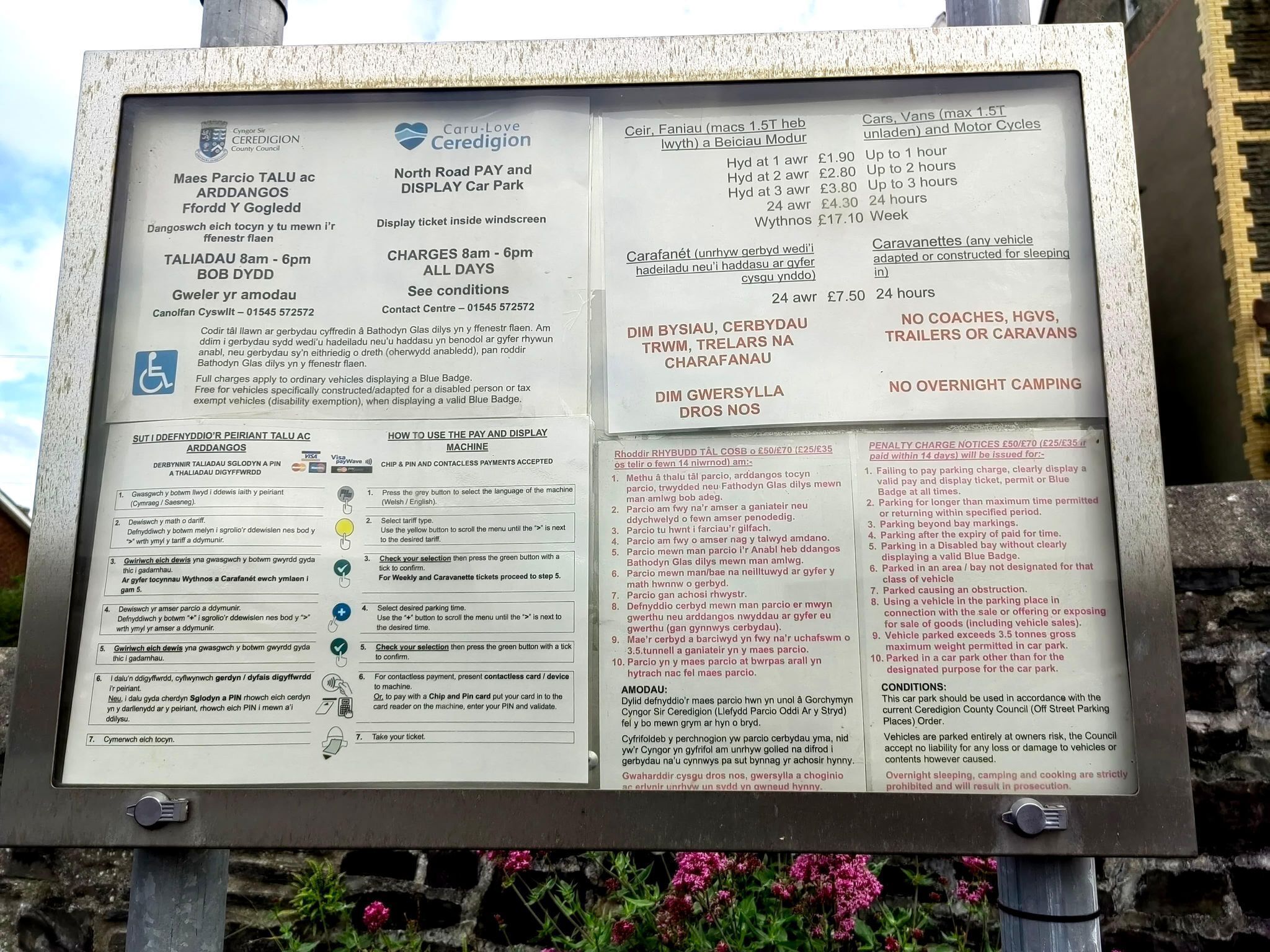 A parking sign with detailed instructions and rates for parking at a car park.