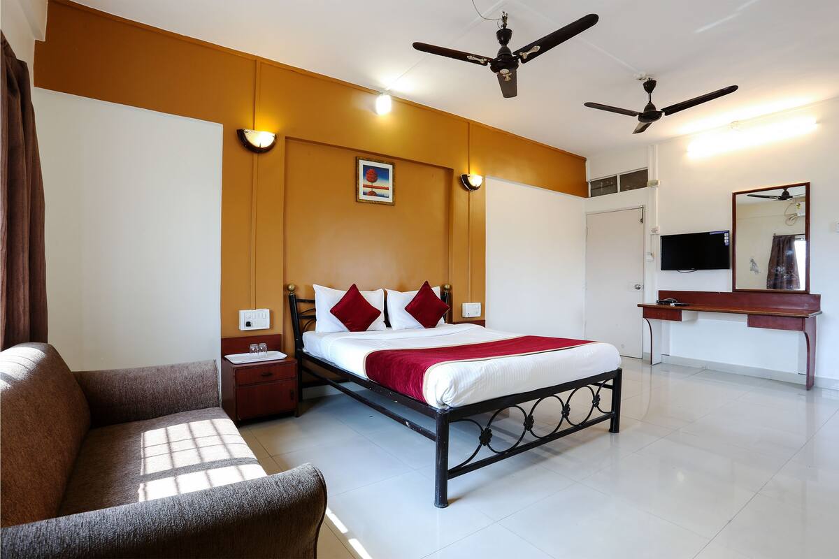 Une chambre d’hôtel équipée d’un lit, d’un canapé, d’un bureau et d’un ventilateur de plafond.