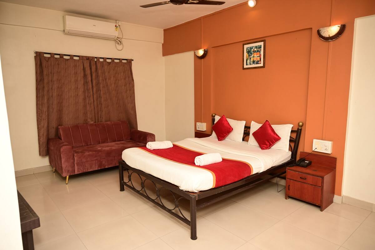 Une chambre bien rangée, avec un lit, un canapé, une table de chevet et une commode.