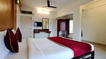 A hotel room with a bed, a desk, a television, and a wardrobe.