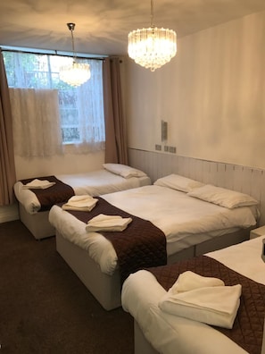 Ein Hotelzimmer mit zwei Betten, einem Chandelier und einem fenster mit Vorhängen.