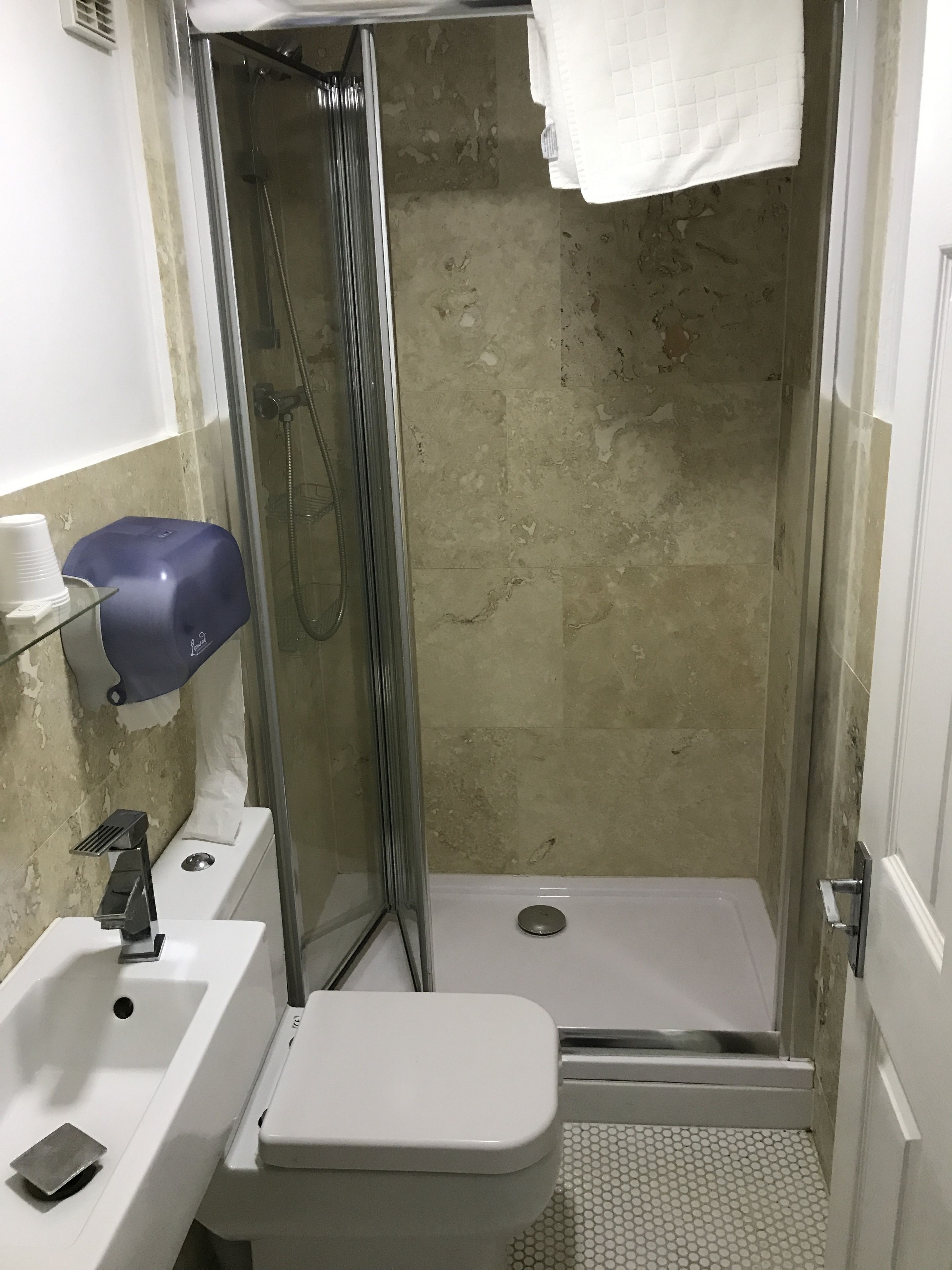 A small bathroom with a shower, sink, and toilet.
