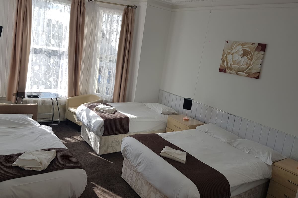 A hotel room with two beds, a chair, a table, and a painting on the wall.