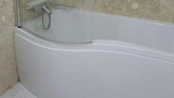 Un bagno con doccia vetrata, una vasca da bagno bianca e un pavimento piastrellato.