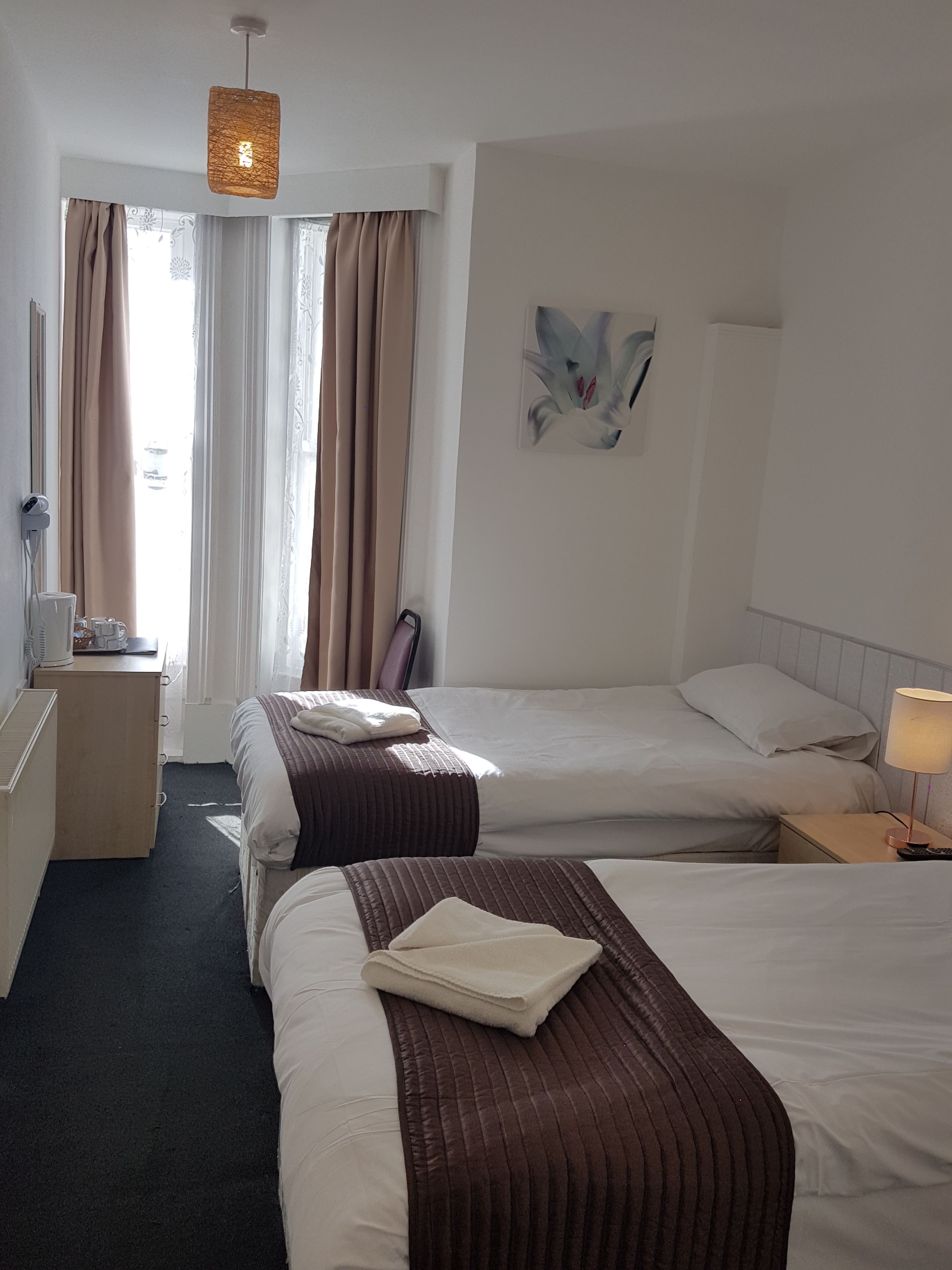 Une chambre d’hôtel avec deux lits, un bureau, une chaise et un tableau au mur.