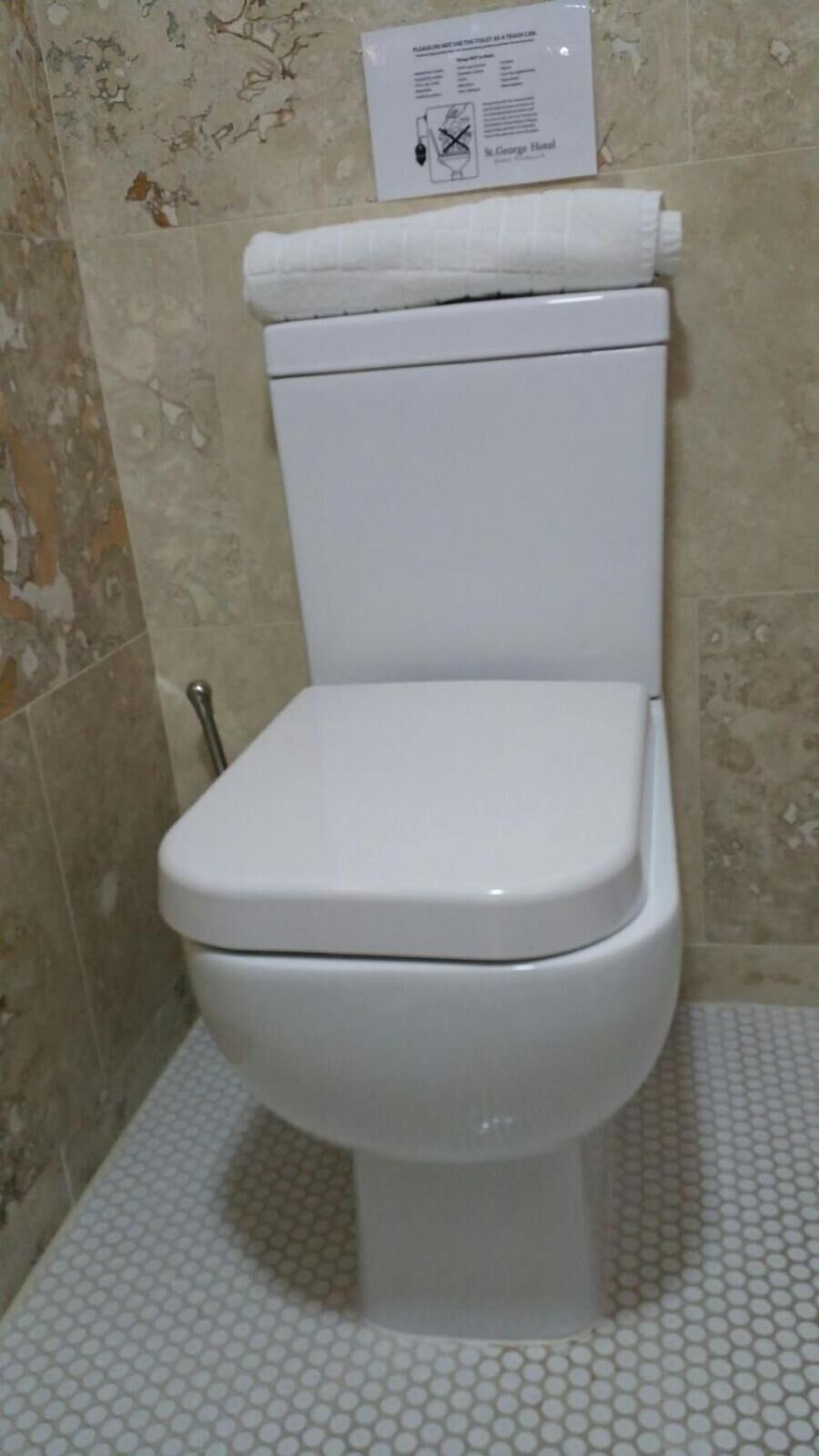 Un inodoro blanco en un baño con baldosas decorativas en las paredes y el suelo.