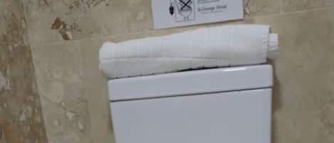 Un inodoro blanco en un baño con baldosas decorativas en las paredes y el suelo.