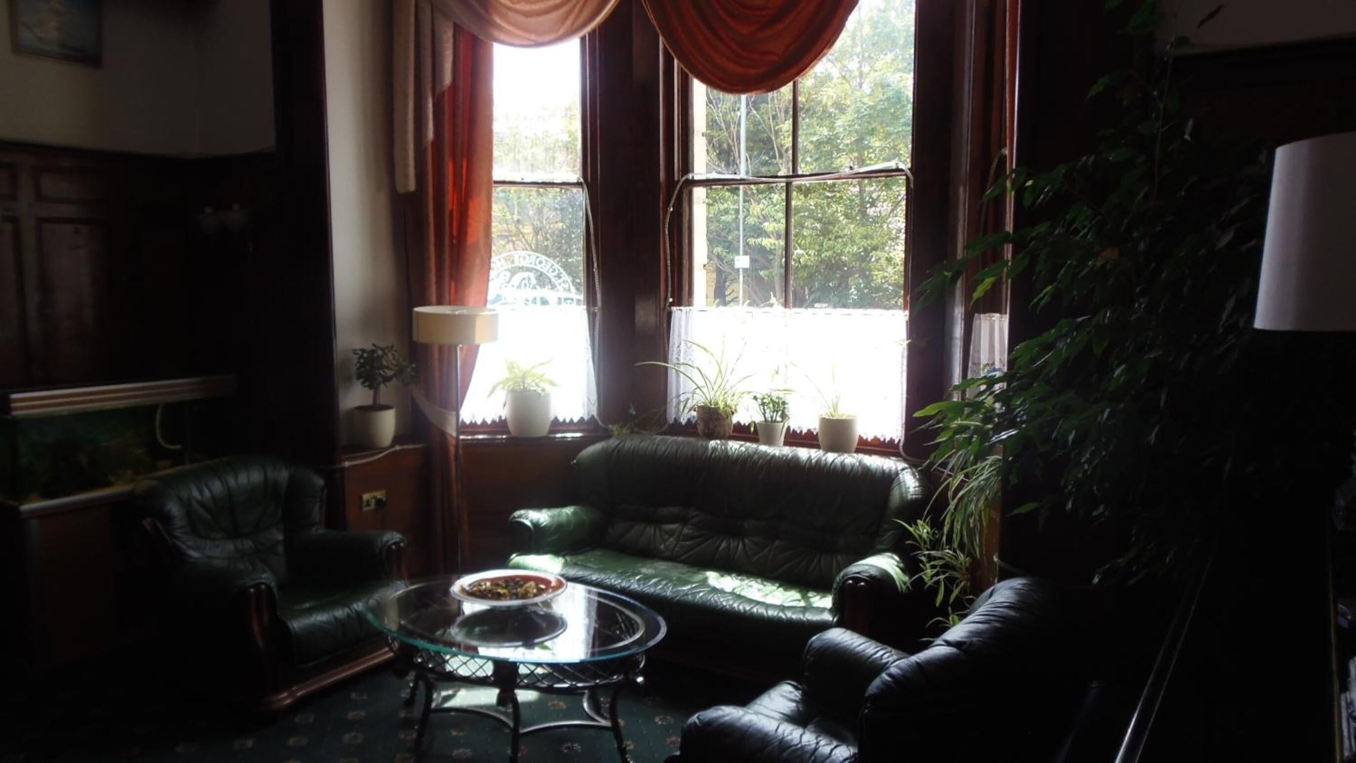 A cozy living room with a leather sofa, a glass coffee table, and a fish tank.